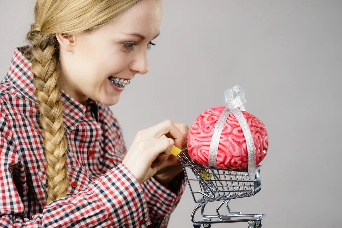 Una mujer coloca un cerebro dentro de un pequeño carrito de compras